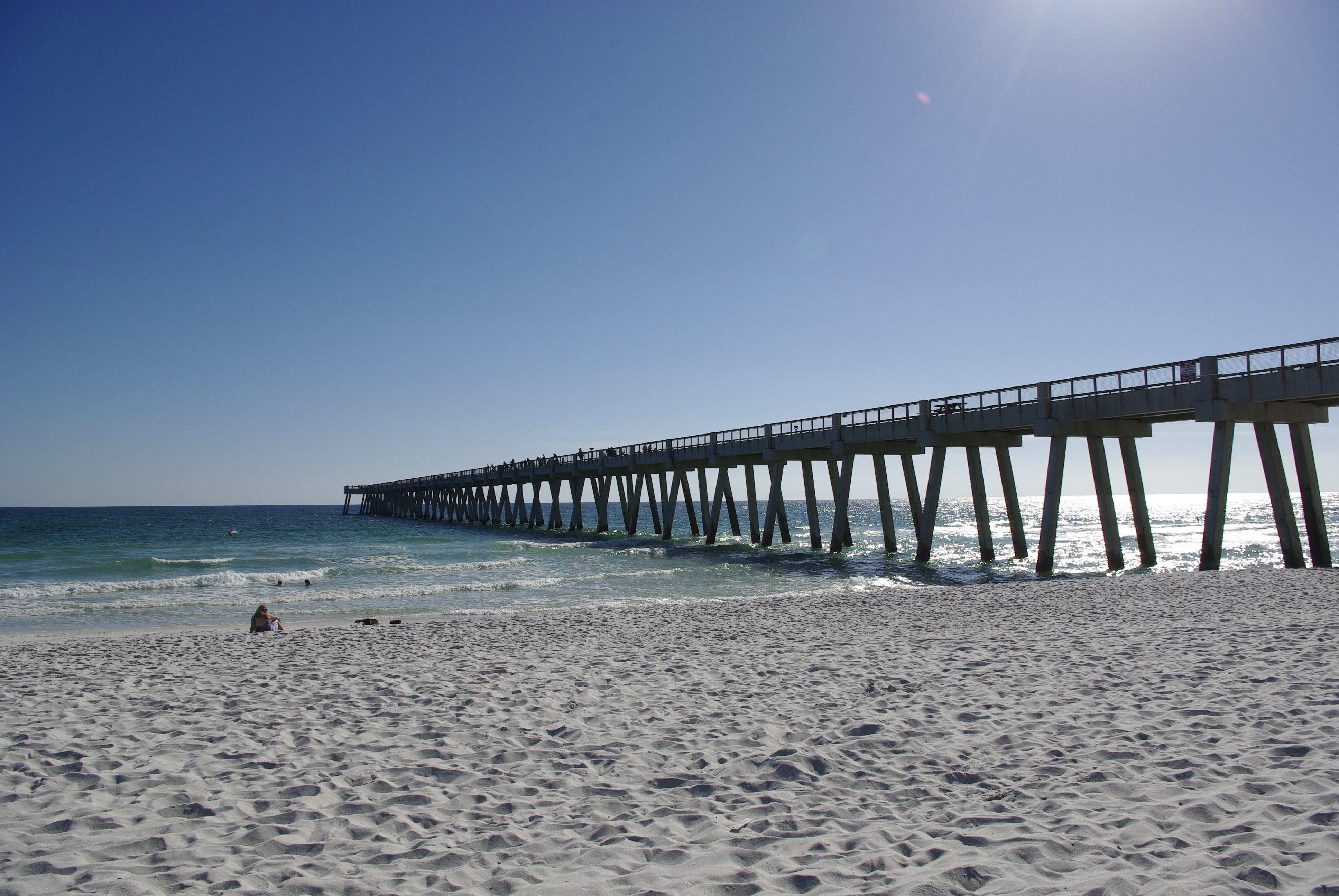 Waves roll onto the white sand beside Navarre Beach Fishing Pier.